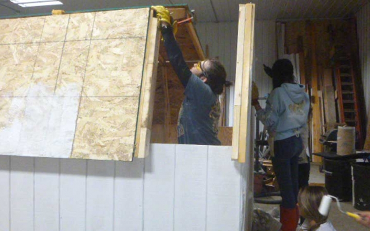 Two people work on a wooden structure during a service project with outward bound. 